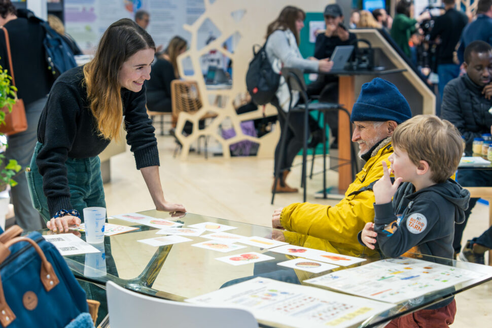 Femme de l'Ademe qui sourit à un enfant et une personne âgée